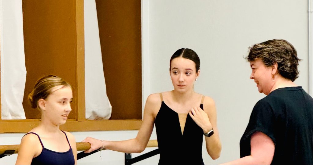 Ballet teacher instructing two young teenage dancers